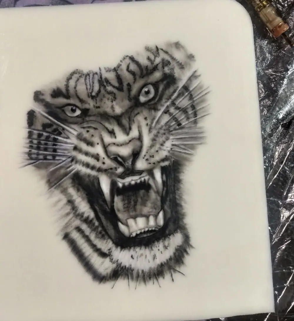 A roaring tiger head in black and grey on practice skin